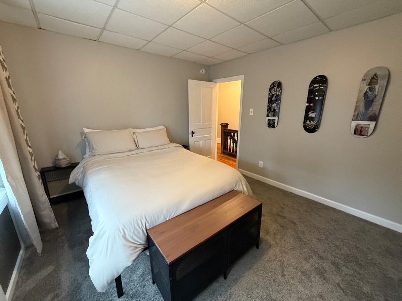 Bedroom with a made queen bed, soft bedding and a storage bench