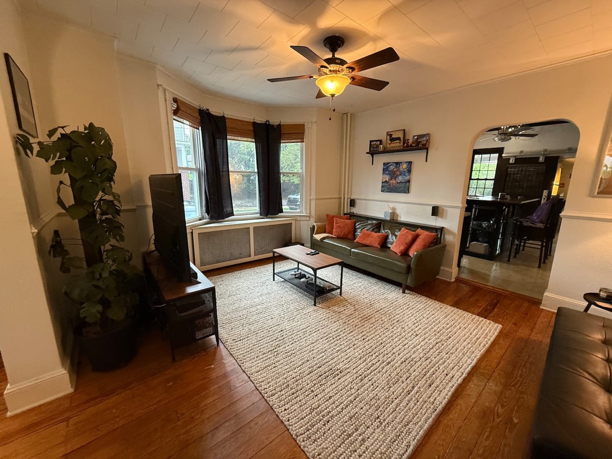 Sunlit living room at Greenwood Hill Getaway with hardwood floors, a sofa and large windows